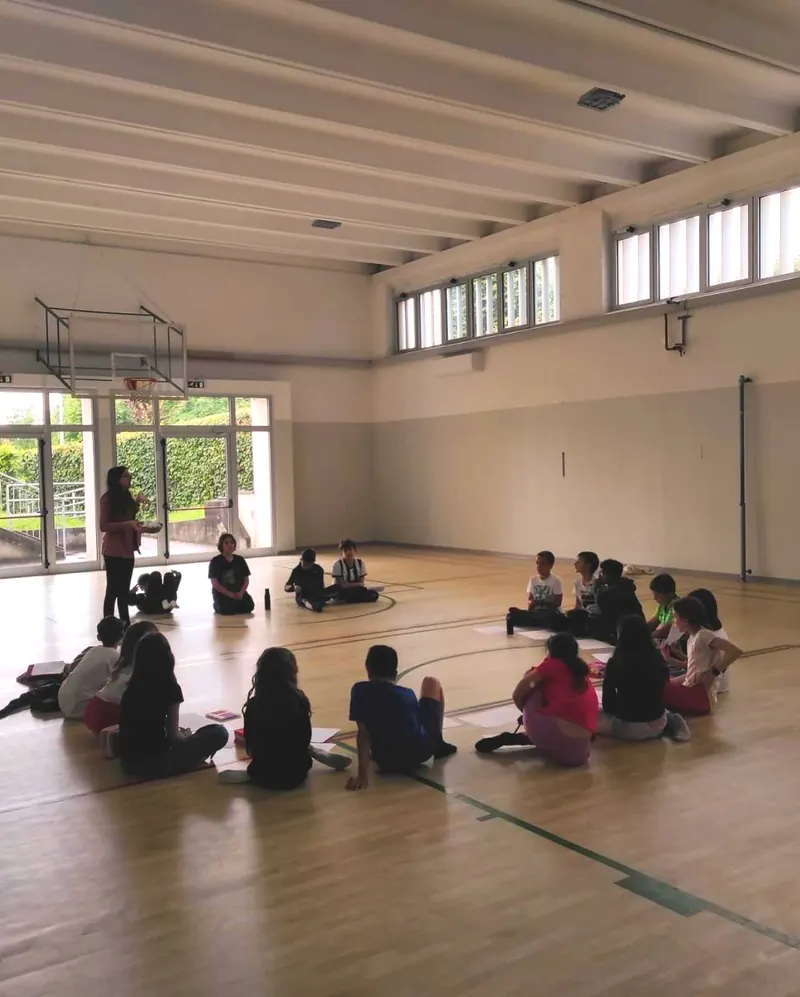 Ragazzi seduti in cerchio a terra in una palestra durante un incontro del percorso